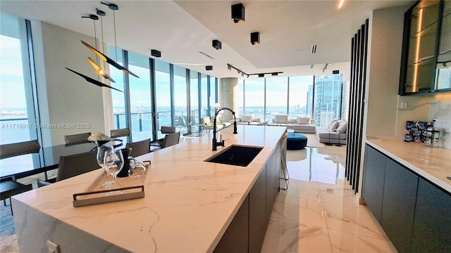 kitchen with a large island, modern cabinets, a sink, open floor plan, and marble finish floor