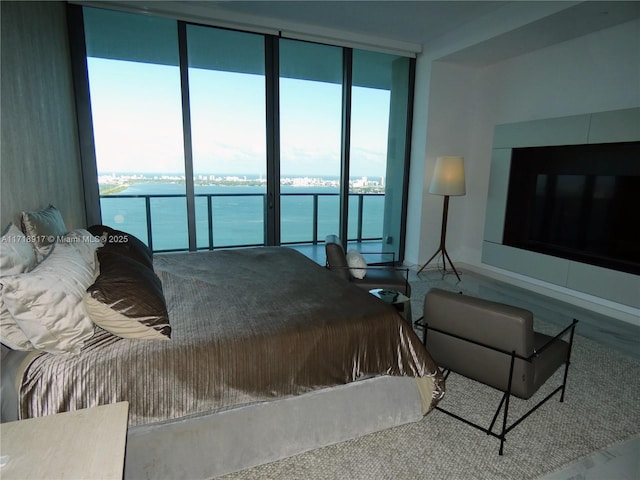 bedroom with access to exterior, a water view, and expansive windows