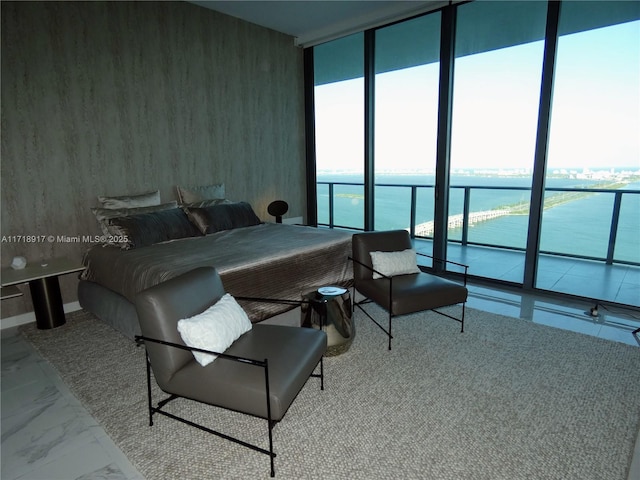 bedroom featuring a water view, marble finish floor, and a wall of windows
