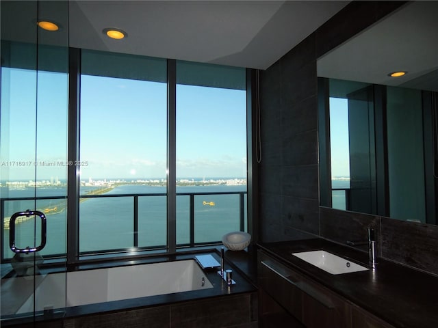 bathroom featuring tiled tub, sink, and a water view