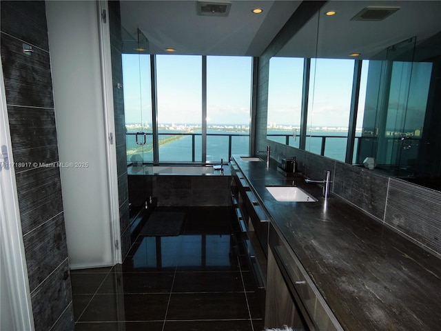 bathroom with tile patterned flooring, double vanity, visible vents, a water view, and a sink
