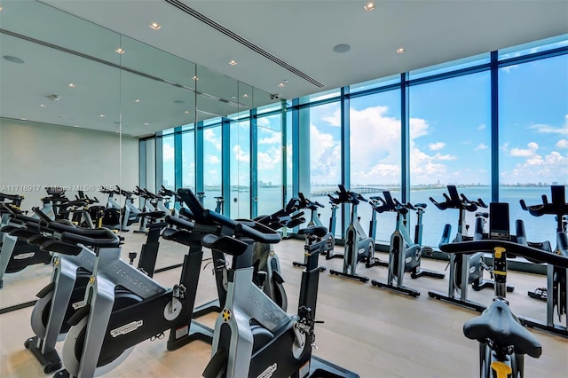 exercise room with floor to ceiling windows, a water view, and a wealth of natural light