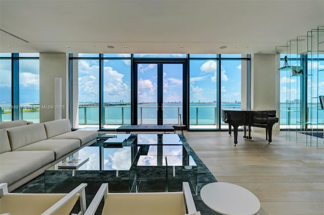 living room with hardwood / wood-style floors, plenty of natural light, floor to ceiling windows, and a water view