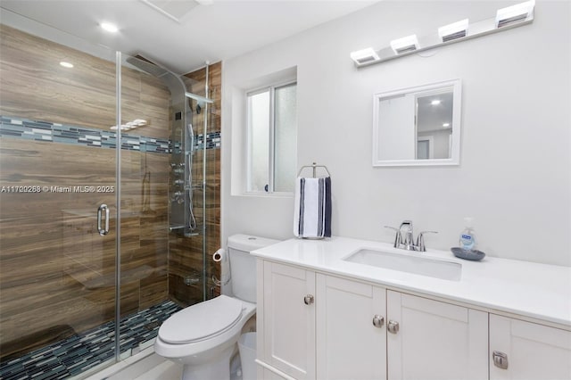 bathroom featuring vanity, toilet, and a shower with door