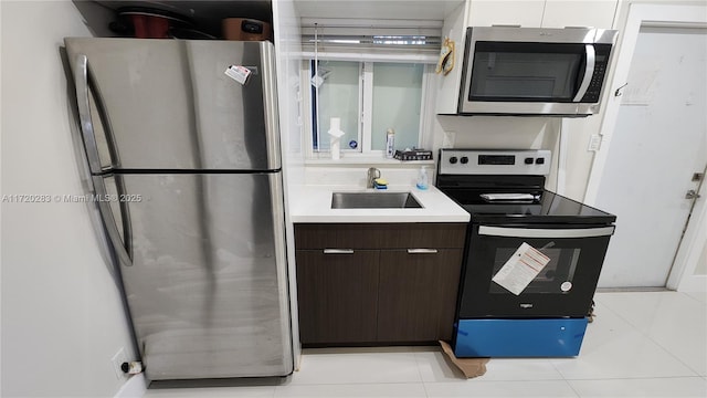 kitchen with white cabinetry, sink, stainless steel appliances, dark brown cabinets, and light tile patterned floors