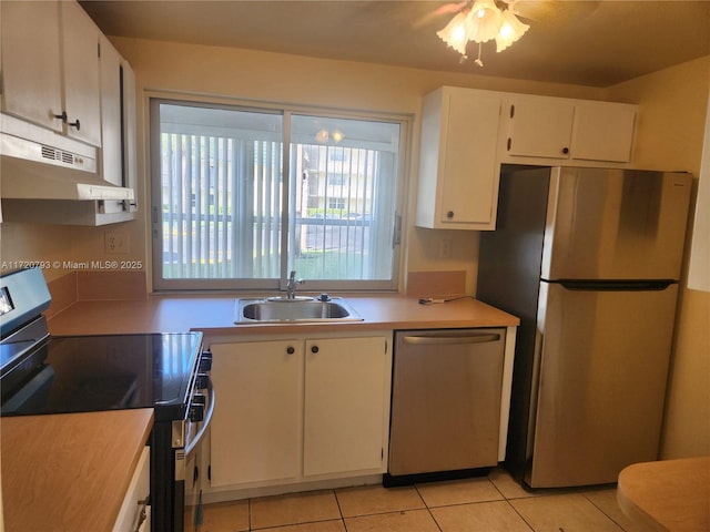 kitchen featuring white cabinetry, sink, light tile patterned floors, and appliances with stainless steel finishes