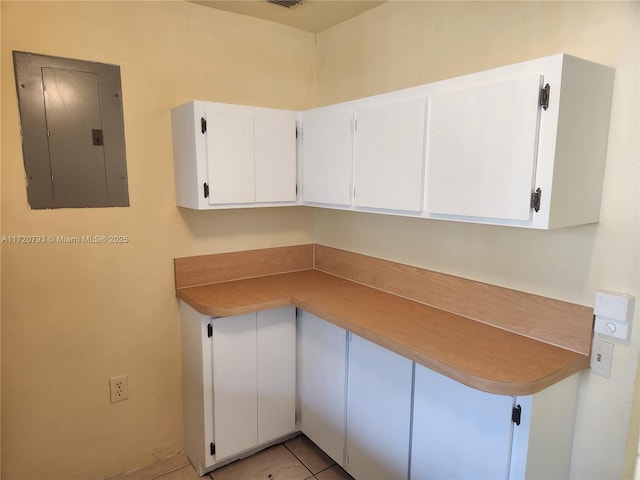 kitchen featuring white cabinets, light tile patterned flooring, and electric panel