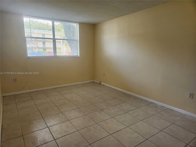 empty room with light tile patterned flooring and a textured ceiling