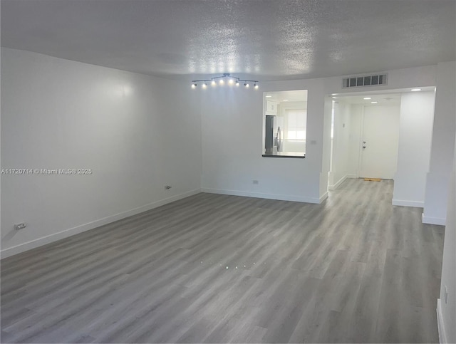 spare room with light wood-type flooring and a textured ceiling