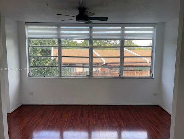 unfurnished room with ceiling fan, dark hardwood / wood-style flooring, and a textured ceiling