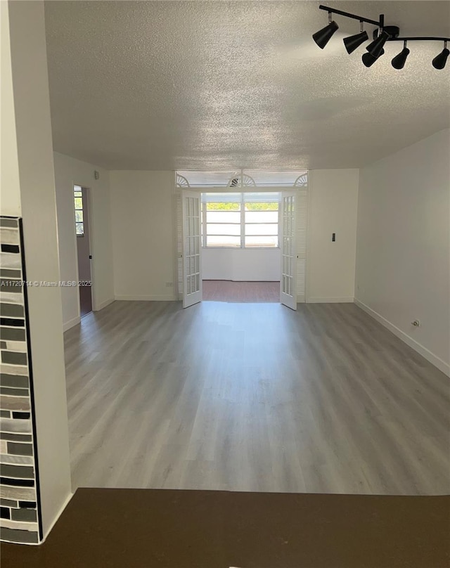 spare room featuring french doors, a textured ceiling, hardwood / wood-style flooring, and track lighting