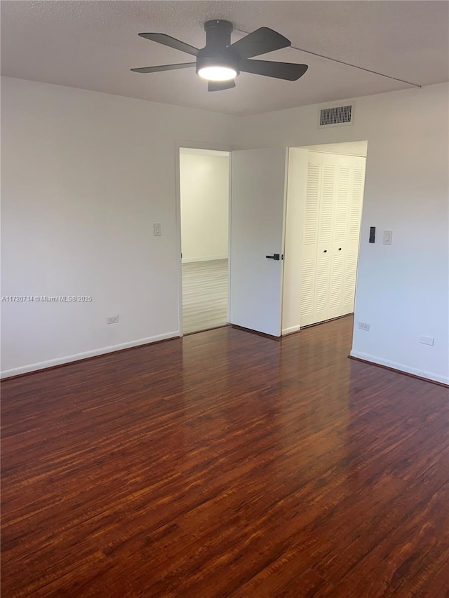 empty room featuring ceiling fan and dark wood-type flooring