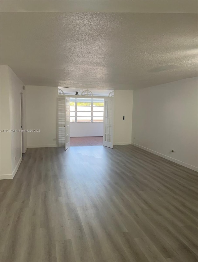 unfurnished room featuring french doors, a textured ceiling, and dark wood-type flooring