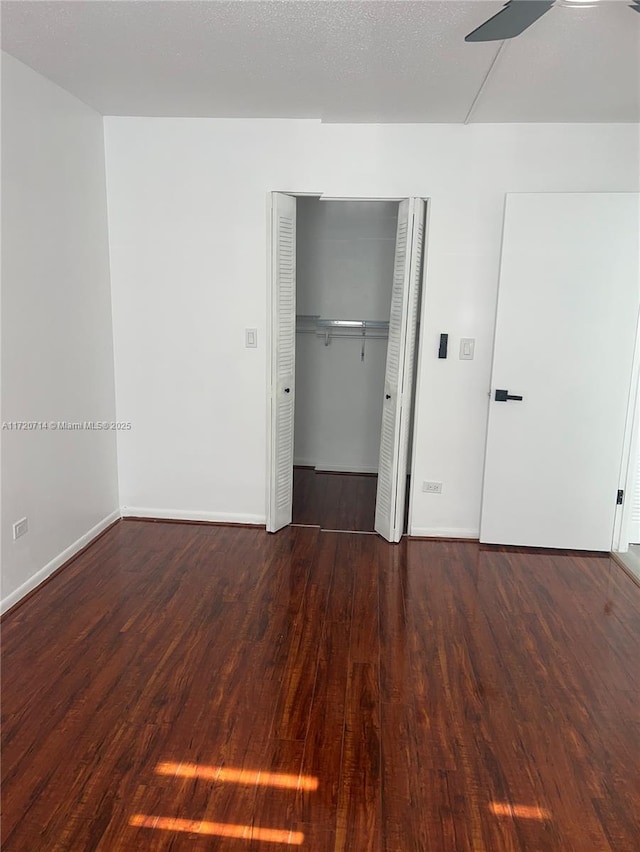 unfurnished bedroom featuring a textured ceiling, dark hardwood / wood-style floors, and ceiling fan