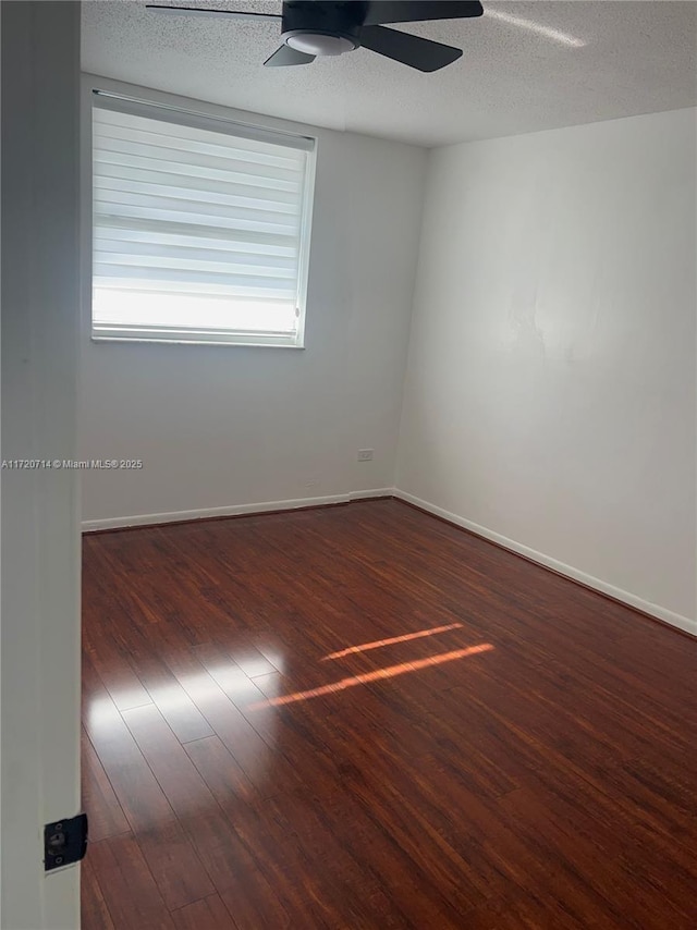 unfurnished room featuring a textured ceiling, ceiling fan, dark wood-type flooring, and a wealth of natural light