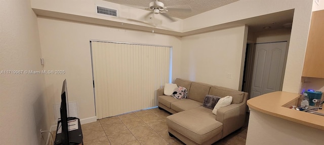 living room with light tile patterned floors, a textured ceiling, and ceiling fan