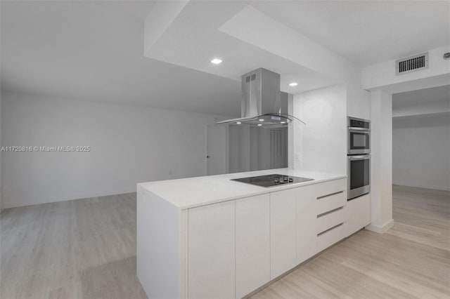 kitchen featuring white cabinetry, double oven, island exhaust hood, black electric stovetop, and light wood-type flooring