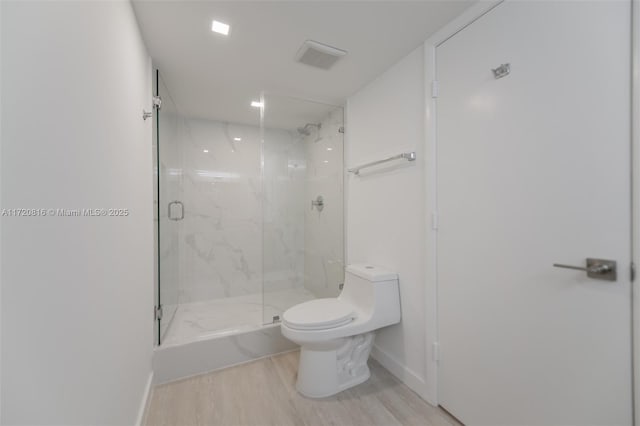 bathroom with toilet, an enclosed shower, and hardwood / wood-style flooring