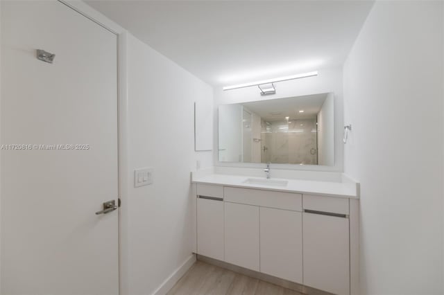 bathroom with walk in shower, vanity, and hardwood / wood-style flooring