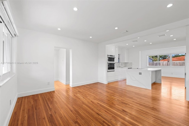 unfurnished living room featuring light hardwood / wood-style flooring and sink