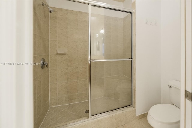 bathroom featuring tile patterned floors, toilet, and an enclosed shower