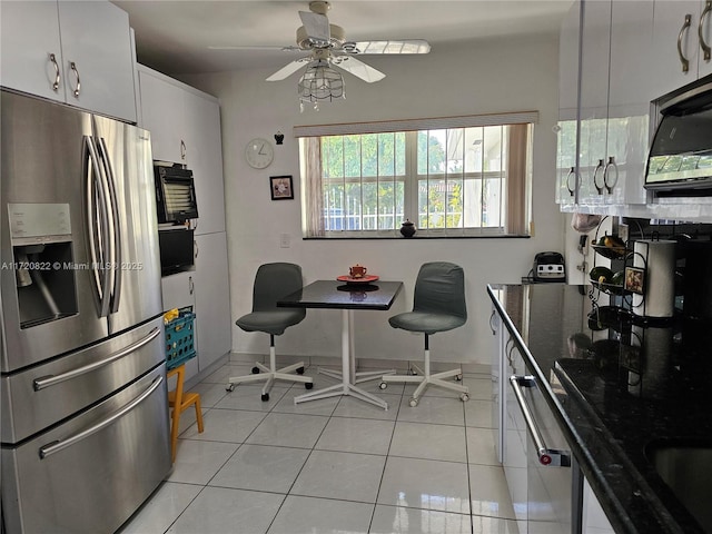 kitchen featuring white cabinets, dark stone counters, stainless steel fridge with ice dispenser, light tile patterned flooring, and ceiling fan