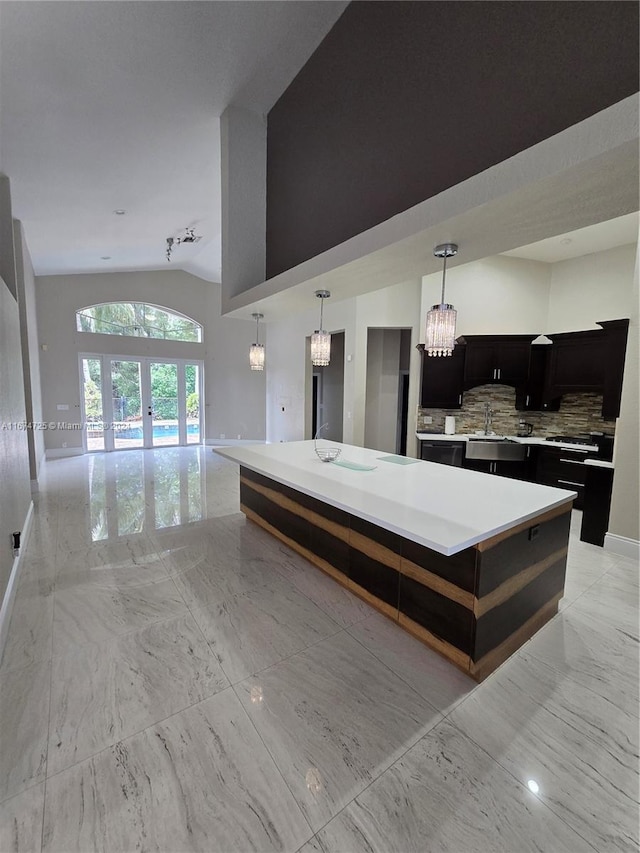 kitchen featuring french doors, tasteful backsplash, sink, a center island, and hanging light fixtures