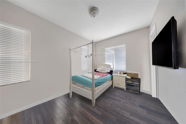 bedroom with dark hardwood / wood-style flooring, a textured ceiling, and a notable chandelier