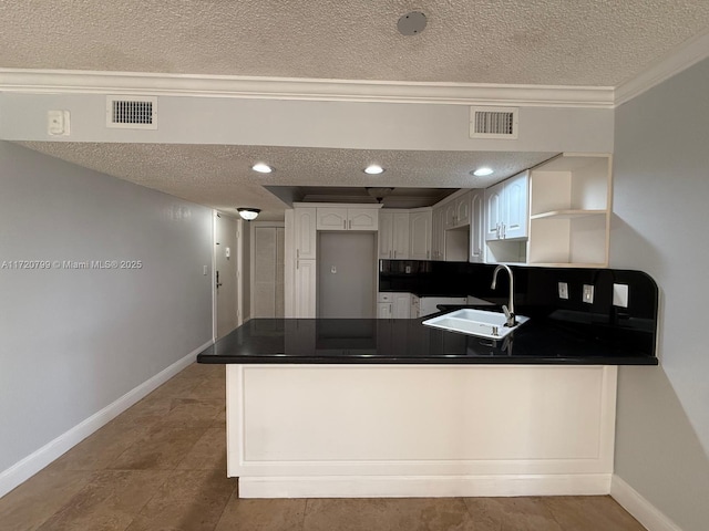 kitchen featuring kitchen peninsula, a textured ceiling, white cabinetry, and sink