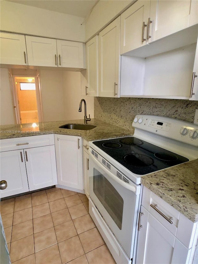 kitchen featuring tasteful backsplash, white range with electric stovetop, sink, light tile patterned floors, and white cabinets