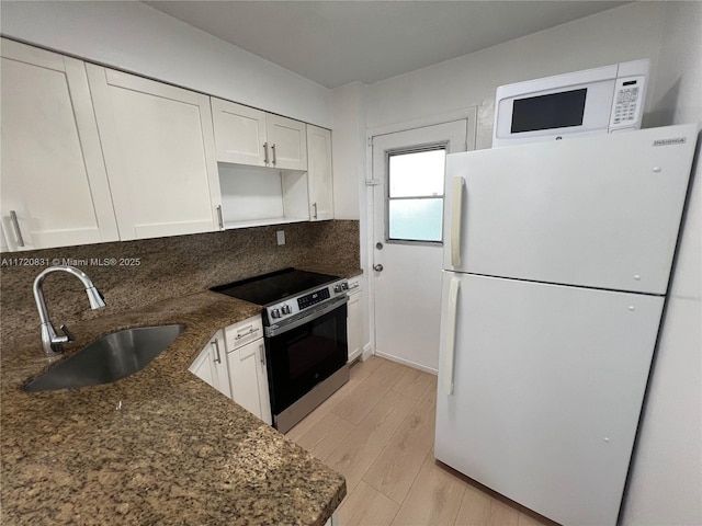 kitchen featuring stainless steel range with electric stovetop, white refrigerator, white cabinetry, and sink