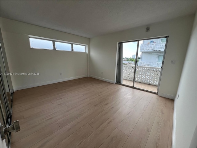 unfurnished room with a textured ceiling, light hardwood / wood-style floors, and a wealth of natural light