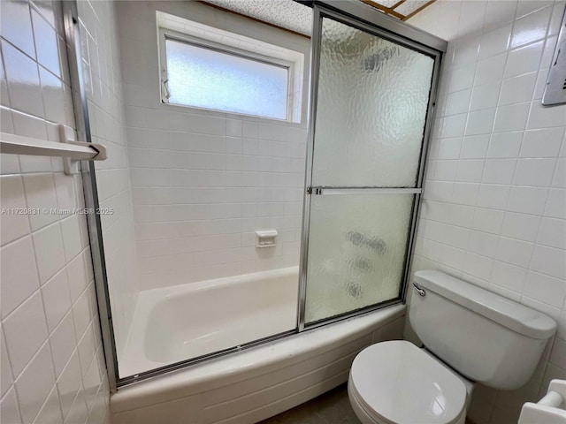 bathroom featuring shower / bath combination with glass door, tile walls, and toilet