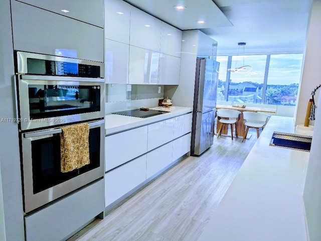 kitchen with stainless steel appliances, modern cabinets, light countertops, and white cabinets