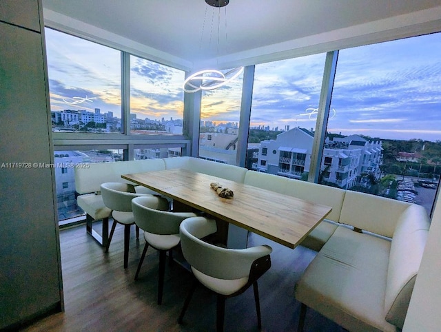 dining area with a view of city, breakfast area, a wall of windows, and wood finished floors