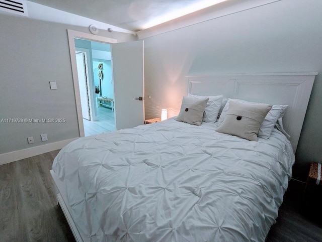 bedroom with baseboards, visible vents, and wood finished floors