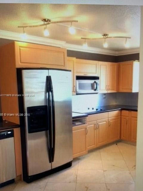 kitchen featuring light tile patterned floors, ornamental molding, track lighting, and appliances with stainless steel finishes