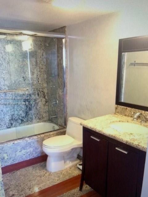 full bathroom featuring vanity, toilet, and combined bath / shower with glass door