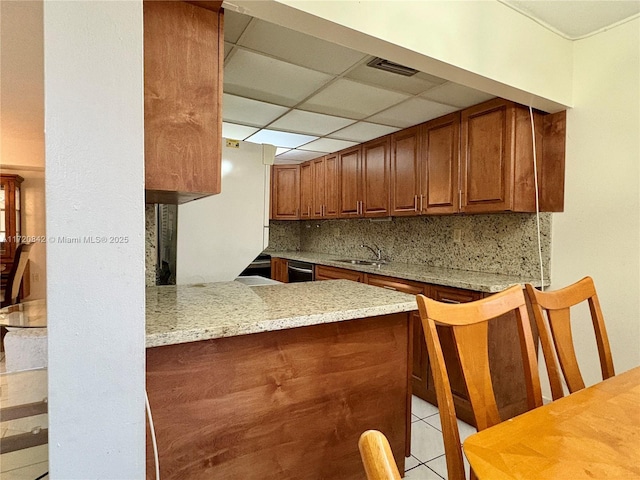 kitchen featuring light stone countertops, kitchen peninsula, a paneled ceiling, tasteful backsplash, and white refrigerator