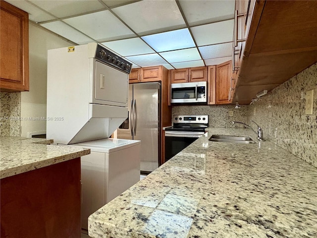 5900 SW 127th Ave Unit 3218, Miami, FL 33183 - kitchen featuring stacked washer / drying machine, a sink, light stone counters, and stainless steel appliances