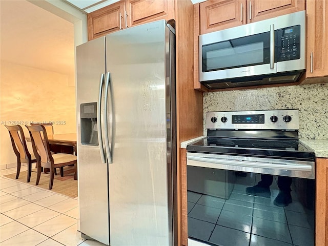 5900 SW 127th Ave Unit 3218, Miami, FL 33183 - kitchen featuring stainless steel appliances, light tile patterned flooring, brown cabinetry, backsplash, and light countertops