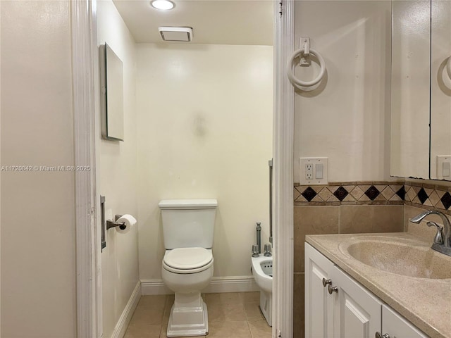 bathroom featuring tile patterned floors, a bidet, toilet, vanity, and tile walls