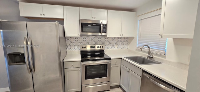 kitchen with decorative backsplash, sink, white cabinets, and appliances with stainless steel finishes