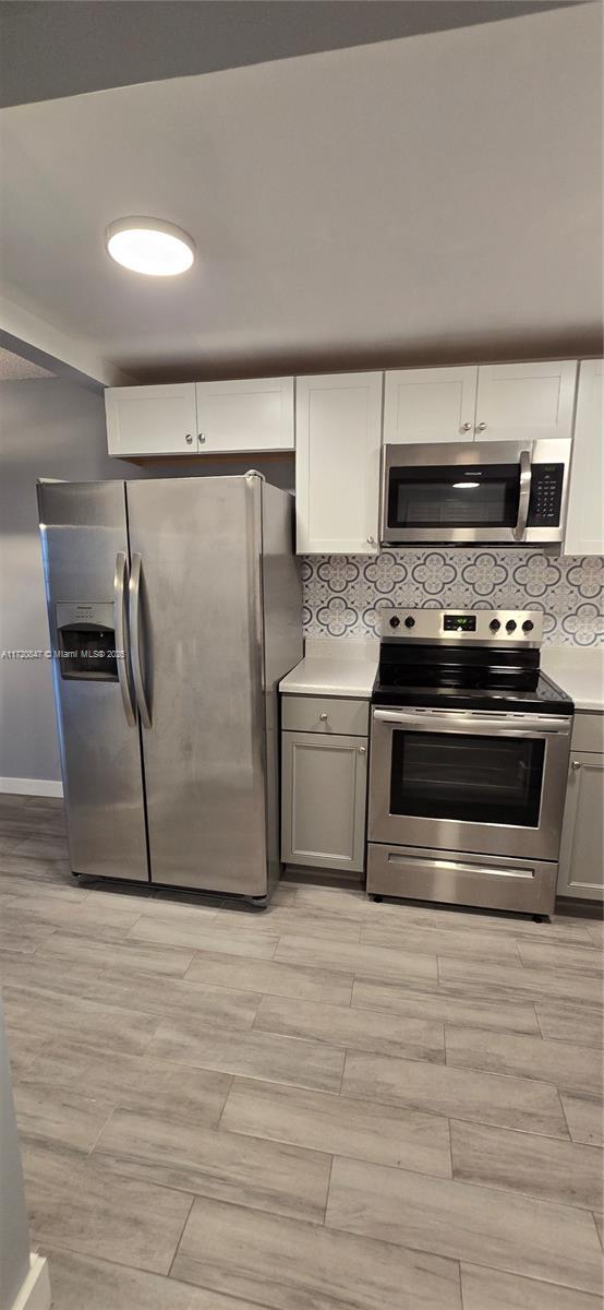 kitchen featuring white cabinets, stainless steel appliances, and gray cabinets