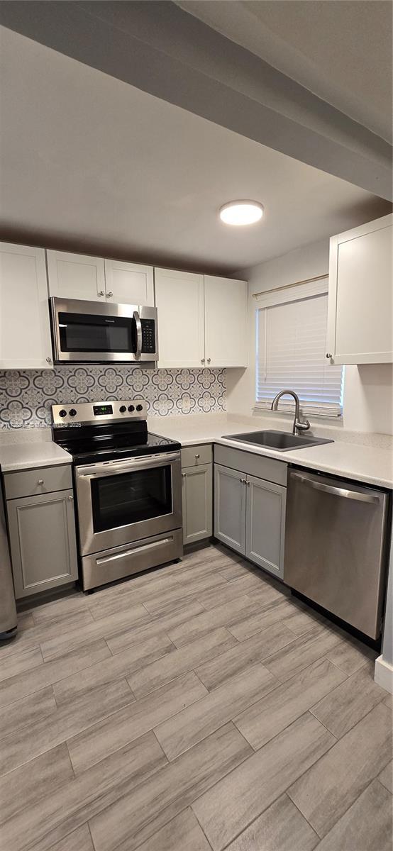 kitchen with gray cabinets, white cabinetry, sink, and stainless steel appliances