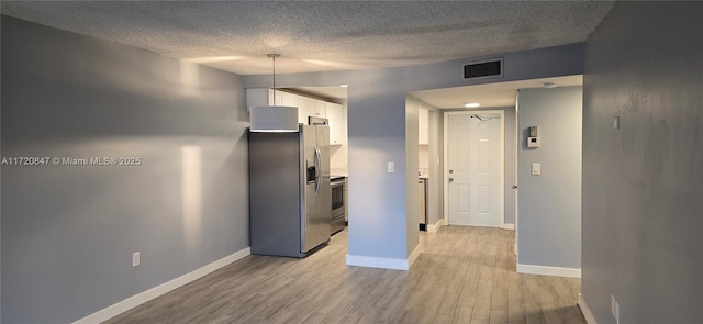 interior space with a textured ceiling and light hardwood / wood-style flooring