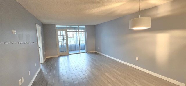 empty room with floor to ceiling windows, wood-type flooring, and a textured ceiling