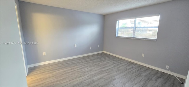 empty room featuring wood-type flooring and a textured ceiling