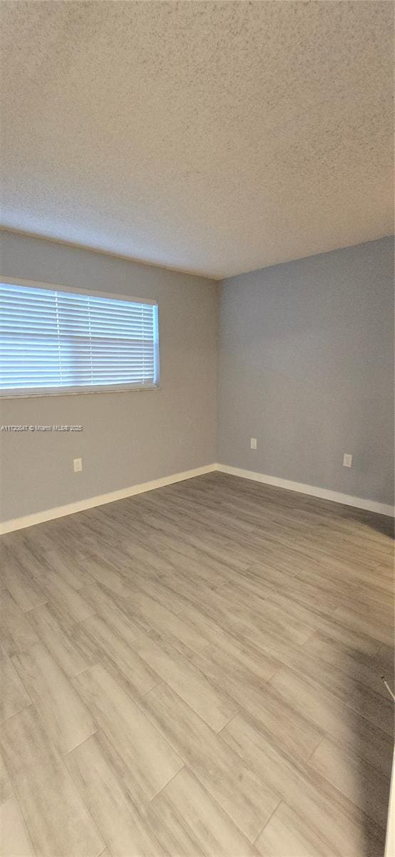 unfurnished room featuring a textured ceiling and light hardwood / wood-style floors