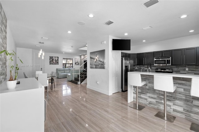 kitchen with appliances with stainless steel finishes, a kitchen breakfast bar, sink, decorative light fixtures, and a kitchen island